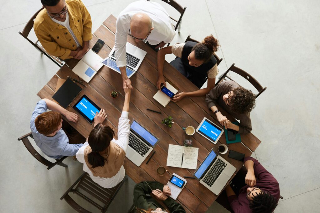 pexels-photo-3183197-3183197 Top view of a diverse team collaborating in an office setting with laptops and tablets, promoting cooperation.